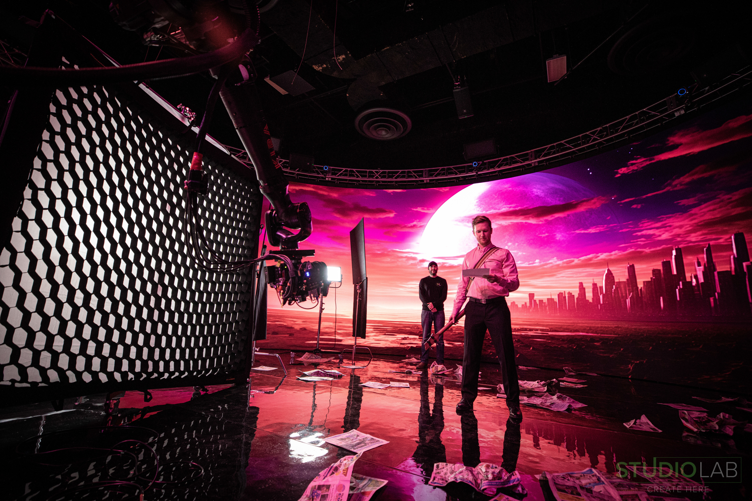 Actor on a futuristic set with a vibrant purple background, filmed with a robotic camera arm in a studio with scattered props.
