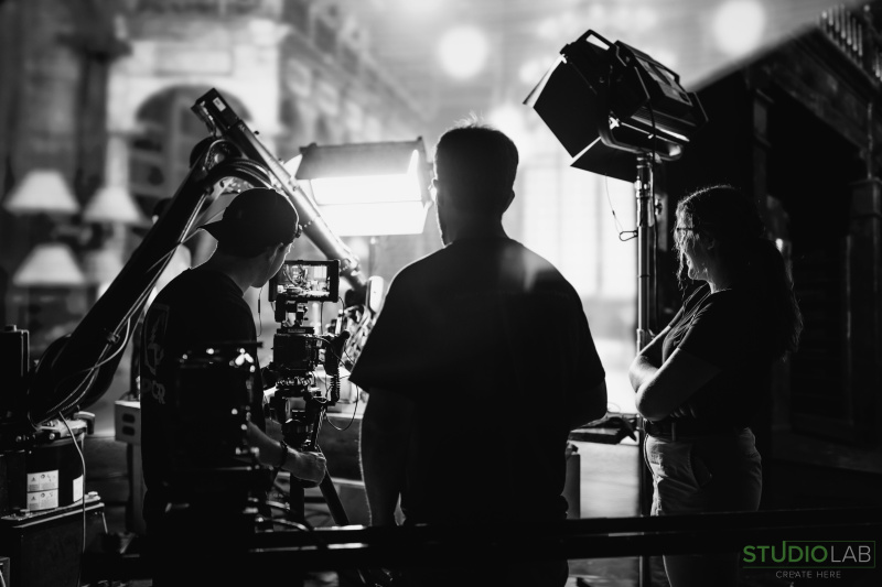 Crew members filming a medieval-themed scene, with dramatic backlighting highlighting the KIRA robot and camera rig.